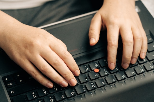 person's hands typing on laptop keyboard for article why keyword research is important